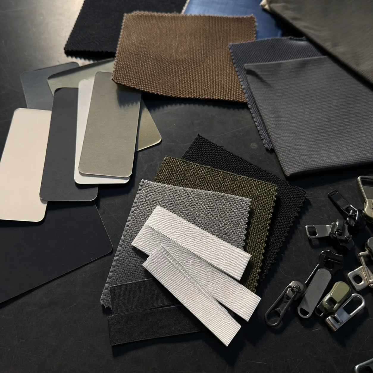 Close view of technical fabric swatches, woven labels, and color cards on a worktable